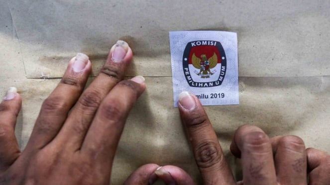 Petugas Kelompok Panitia Pemungutan Suara (KPPS) menyegel amplop yang berisi surat suara sebelum didistribusikan ke kelurahan di gudang logistik KPU Jakarta Pusat, GOR Kemayoran, Jakarta